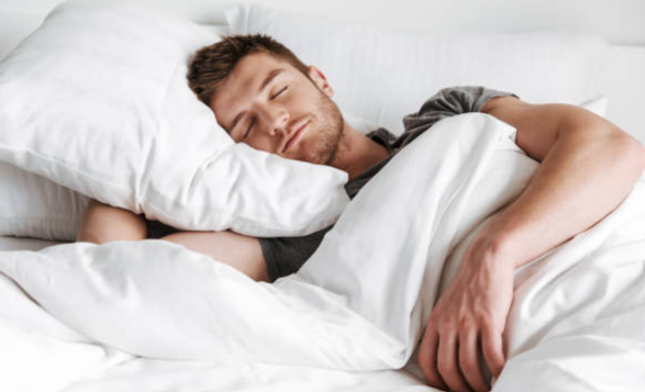 Man sleeping peacefully in a bed with white pillows and blankets