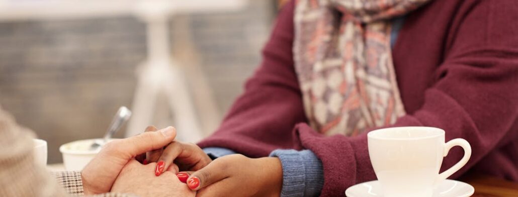 Two people holding hands and having coffee, talking about childhood trauma and depression