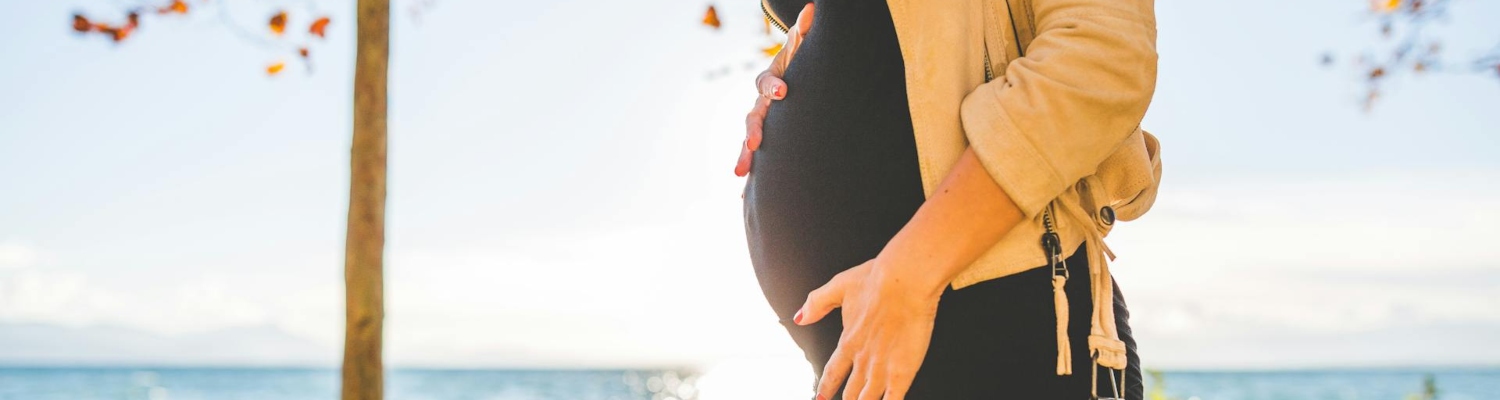 a pregnant woman touching her belly and thinking about common depression triggers 