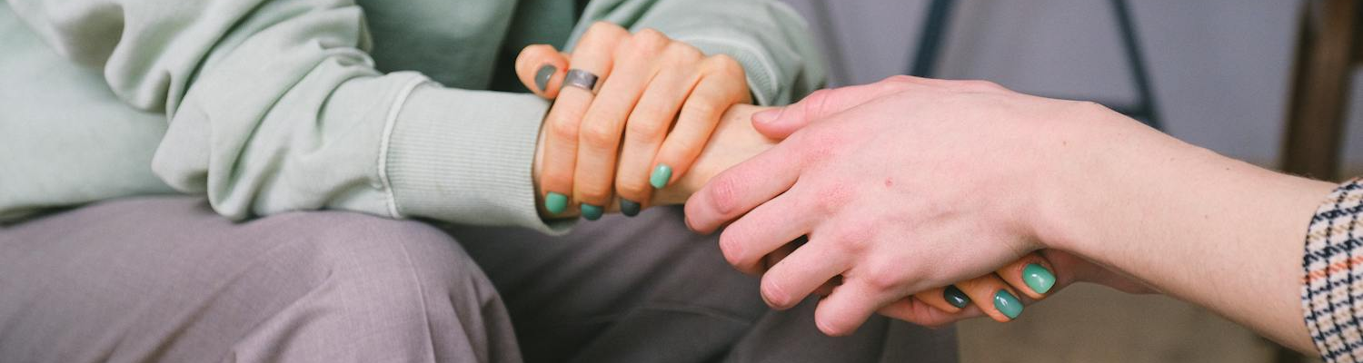 Two women holding hands in support. 